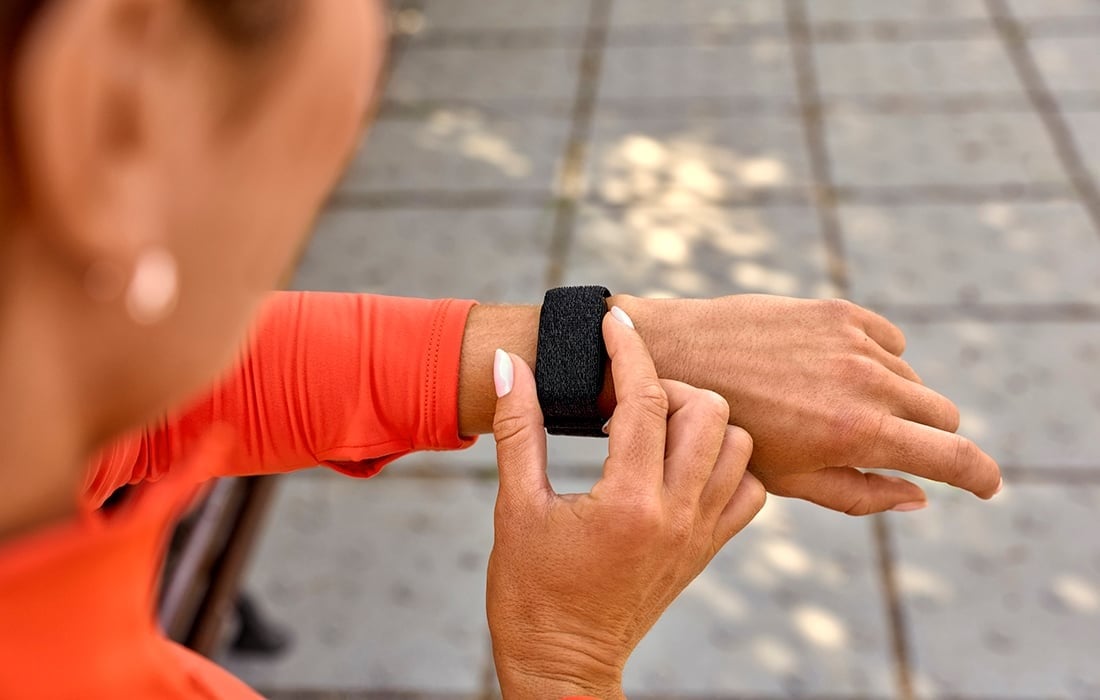 Seseorang sedang menekan tombol di bagian samping CIRQA Smart Band sebelum memulai aktivitas. Smart band tersebut terpasang di pergelangan tangan.